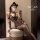 Woman in leopard print lingerie set with matching gloves and cat ears, sitting on a stool.