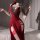 Woman in red lace-trimmed qipao-style lingerie set, holding black fan — elegant sleepwear for intimate moments.