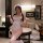 Woman wearing white cherry print lingerie set with lace trim, headpiece, and thigh-highs in a cozy bedroom setting.