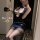 Woman in mirror selfie wearing navy blue airline-themed lingerie set with skirt, sheer stockings, and matching hat.
