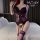 Woman in bedroom wearing purple and black lace lingerie set with open-crotch vest bra, holding red rose.