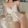 Woman wearing white lace lingerie set with bow detail, lying on bed - pure & seductive sleepwear outfit for intimate moments.