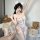A woman poses in a playful pose wearing a floral-patterned sleepwear set with adjustable straps, featuring cute bunny ears an...