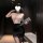 Woman wearing pure & seductive lingerie set – secretary-style lace top and pencil skirt, holding clutch in dim room.