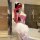 Woman in red and white nurse costume with lace bodysuit, heart details, sheer gloves, tutu skirt, and thigh-high stockings.