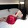 Woman wearing red lace qipao lingerie set on bed, back view showing strappy design and sheer fabric.