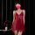 A woman wears a red sheer mesh bralette sleep dress with lace trim and side slit, exuding sensuality and elegance.