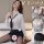 Woman modeling white sheer secretary-style shirt with black tie, mini skirt and stockings on bed.