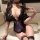 Woman wearing black lace lingerie set with purple accents, featuring a deep v-neck bodysuit and fishnet stockings.