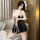 A woman poses elegantly wearing a black satin sleep dress with lace detailing, featuring a sexy backless slit and adjustable ...