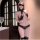 Woman wearing black lace bodysuit with sheer cutouts and bondage-inspired design, paired with thigh-high stockings and a blin...