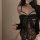 Woman wearing black lace bodysuit with bow, holding champagne flute. sheer see-through design with cut-out details.