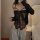 Woman wearing black lace bodysuit with bow, sheer panels and cut-outs, styled as sexy uniform with gray sweatpants.