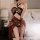 A woman poses in a sheer lace bondage nightwear set, featuring a halter top and thigh-high skirt, designed for sensual allure...
