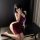 A woman poses elegantly in a deep red satin sleep dress featuring a halter neck and lace detailing, exuding allure and sophis...