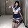 Woman kneeling in white and navy sailor-style crop top with bow, matching pleated skirt, and black lace-top thigh-high stocki...