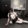 A woman poses seductively in a modern room, wearing a white blouse with a black skirt, lace stockings, and holding a phone. t...