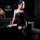 Woman in black sheer bodysuit with lace details and thigh-high stockings, posing in a modern bathroom. pure & tempting linger...