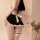 Woman wearing black and white maid-style lingerie set with ruffles, bow, and garter; pure & tempting sexy nightwear.
