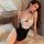 A woman poses elegantly wearing a sheer black maid costume bodysuit adorned with lace details and a bow, perfect for small bu...