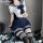 A woman poses wearing a schoolgirl uniform set, featuring a sailor-style top with a bow tie and pleated skirt, paired with st...