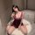 Woman wearing pure & tempting deep v lace sleep dress with sheer mesh and high slit, seated on white rug in modern room.