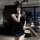 A woman poses elegantly in a black bodycon sleepwear set featuring a halter neck design and sheer black stockings, set agains...