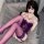 Woman wearing purple lace corset bodysuit with matching garter stockings, lying on gray sofa — seductive shapewear sleepwear ...