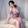 Woman wearing purple lace halter lingerie dress with open-crotch design, floral hair accessory, sitting on white fur rug.
