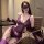 Woman modeling purple lace lingerie set with sheer embroidered bra, panties, gloves, and garter straps in office chair.
