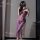 Woman wearing purple lace lingerie set with sheer straps, slit skirt, and floral hair accessory in soft lighting.