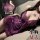 Woman wearing purple lace lingerie sleep dress with sheer details and bow accents, flirty feminine bedroom outfit.