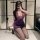 A woman poses in a purple ol secretary lingerie set featuring a deep v neckline, sheer lace bodice, and a form-fitting bodyco...