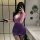 A woman poses in a bathroom wearing a purple ol secretary sexy lingerie set, featuring a deep v lace sheer tight bodycon skir...