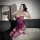 Woman wearing purple plus size lace bodysuit with underwire and open-crotch design, kneeling on white rug while taking mirror...