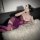 Woman wearing purple plus size lace bodysuit with underwire and open-crotch design, lying on white fur rug while taking a mir...