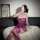 Woman in purple plus size lace bodysuit with underwire and open-crotch design, posing on white fur rug.