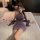 A woman poses on a bed wearing a purple sheer chinese-inspired lingerie set, featuring a sensual modern qipao design with fri...
