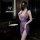 Woman in purple sheer lingerie set with deep v neck and lace detail, posing in modern bathroom.