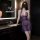 Woman in purple sheer lingerie set with deep v neck, posing in modern bathroom.