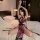A woman poses on a bed wearing a purple high-slit cheongsam lingerie set, featuring sheer fabric and black lace details. the ...