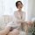A woman sits elegantly wearing a sheer white robe with lace sleeves, perfect for intimate sleepwear and loungewear.