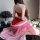 A woman sits elegantly wearing a red and pink qiaoduo hanfu-inspired bodysuit with a sheer skirt, embodying a sexy fox spirit...