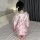 A woman sits on a bed wearing a pink qiaoduo temptation kimono set, featuring anime-inspired designs and lace details. the si...