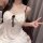 A woman wearing a white cherry print lace-trimmed cami slip dress with black spaghetti straps, featuring a bow detail and bui...