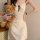 A woman holds a teddy bear while wearing a cream cherry print cami slip dress with lace trim and built-in pads, exuding elega...