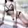 Woman wearing black lace qingran lingerie set with pearl details and pink bows, posing on white bed.