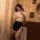 A woman poses elegantly in a vintage-themed setting, wearing a white blouse with gold buttons and a black mini skirt featurin...