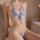 Woman wearing light blue lace lingerie set with open-crotch bikini bottom and halter top, featuring delicate floral embroider...