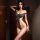 Woman modeling qingran sexy bodysuit with open-crotch design and sheer side panels in a dimly lit room.